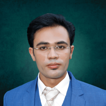 Close portrait of founder and CEO Mr. Hassan in Blue coat standing Infront of green wall